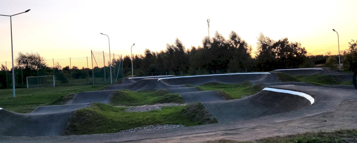 Na zdjęciu widok pumptracku w Skubiance z latarniami i boiskiem w tle