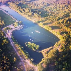 fot. https://trzciany.wakefamily.pl/. Na zdjęciu jezioro otoczone lasem oraz wyciągi do wakeboardu