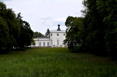 Na zdjęciu w tle Pałac w Jabłonnie, otoczony parkiem krajobrazowym z rozległym trawnikiem i drzewostanem