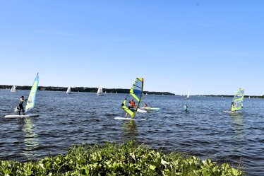 LSURF Szkoła Windsurfingu Kompleks Rekreacyjno - Wypoczynkowy Nieporęt Pilawa (ul. Aleja Wojska Polskiego 3). Osoby pływające na deskach windsurfingowych