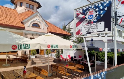 fot. facebook B&B Route 66. Na zdjęciu budynek restauracji B&B Route 66. Pod  parasolami stoliki z ławkami, baner reklamowy American B&B Route 66 Restaurant