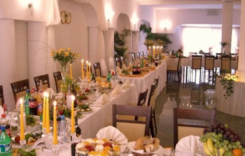 Powiększ obraz: fot. www.domweselnylanda.pl/, Na zdjęciu sala restauracyjna w Domu Weselnym Landa , stoły zastawione jedzeniem, napojami, świeczniki na stołach