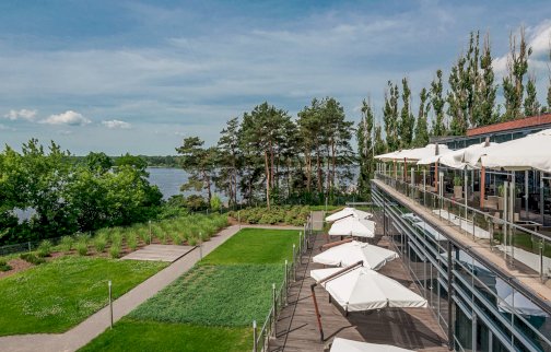 fot. yachtclub.com.pl. Na zdjęciu restauracja Yacht Club. Taras, parasole z wysięgnikami, trawnik, ogródek