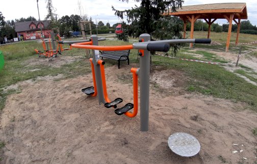 fot. www.nieporet.pl/spolecznosc-gminna/nowe-silownie-plenerowe/. Na zdjęciu siłownia plenerowa: biegacz, wahadło, twister, z tyłu orbitrek, wioślarz