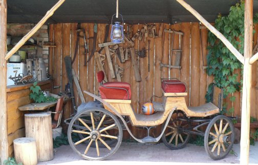 fot. agroturystykajadwisin.mazowsze.pl/miniskansen.html. Na zdjęciu wóz z dużymi kołami z miejscem do siedzenia, wyposażenie mini-skansenu