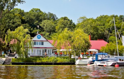 fot. www.klubmila.pl/klub-mila-zegrzynek. Na zdjęciu budynek hotelowy Klubu Mila w Zegrzynku, łodzie, hotel otoczony lasem