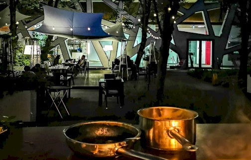 fot. www.hotelnarvil.pl/restauracja/filozofia. Na zdjęciu widok na restaurację Aruana Restaurant, osoby siedzące przy stolikach, garnek, patelnia