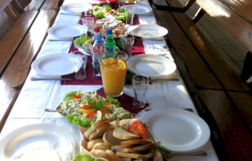 fot. www.water-club.pl/restauracja/restauracja-barka. Na zdjęciu jedzenie, sałatki, przekąski, napoje na stole, ławki do siedzenia