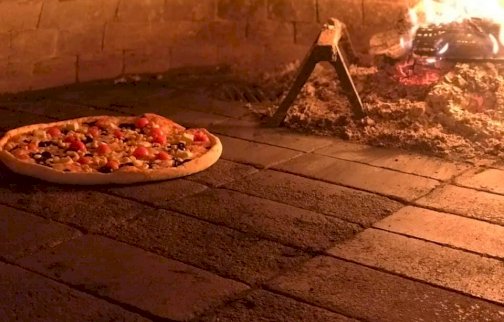 fot. gastronomiahabanero.pl/. Na zdjęciu pizza obok piec opalany drewnem, w tle ogień