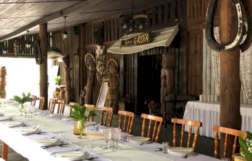 fot. facebook Rancho Bena, www.facebook.com/RanchoBena. Na zdjęciu przygotowana zastawa stołowa na stole, talerze, sztućce, wazony, podkowy zawieszone na drewnianych belkach