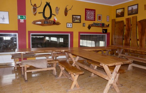 fot. www.stajniaklucz.pl. Na zdjęciu stoły z ławkami do siedzenia, lustra, poroża, obrazy na ścianie