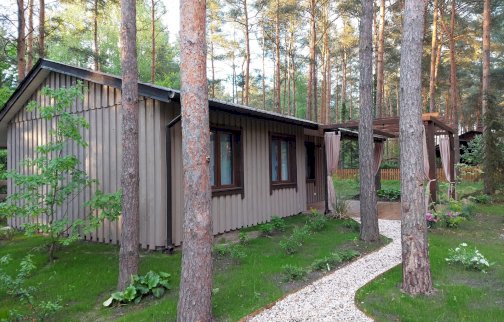 fot. zakatekwytchnienia.pl. Na zdjęciu w otoczeniu drzew domek - Zakątek Wytchnienia