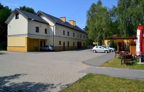 fot. www.zajazdross.pl/. Na zdjęciu zajazd "ROSS" w Nieporęcie, parking obok zajazdu, stoliki z krzesełkami, wiata, zwinięty parasol