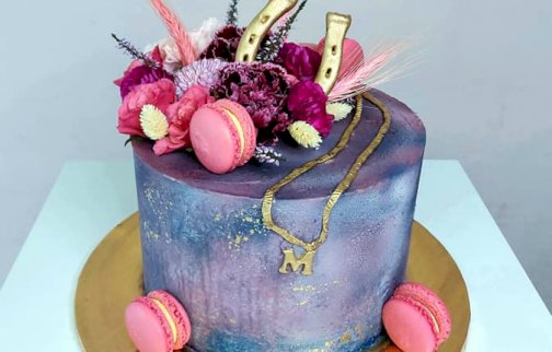 fot. facebook Tortolina Karolina Kornacka -torty artystyczne, https://www.facebook.com/p/Tortolina-Karolina-Kornacka-torty-artystyczne-100064054534438/?locale=pl_PL. Na zdjęciu tort z ciastkami, ozdobami na wierzchu tortu - w kształcie kwiatów, podkowy