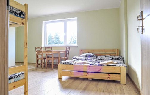 fot. wwww.farmaserock.pl/pokoje/pokoj-nr-14/. Na zdjęciu łóżko, łóżko piętrowe, stolik z krzesłami przy oknie