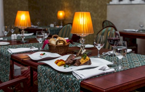 fot. www.windsorhotel.pl/restauracja-hotel-windsor. Na zdjęciu zastawa stołowa na stole, kieliszki, lampki