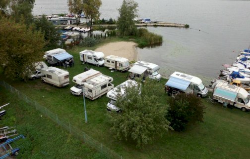 fot. facebook Przystań Przy Starym Moście, www.facebook.com/Przysta%C5%84-Przy-Starym-Mo%C5%9Bcie-420197228031954/photos/516975385020804. Kampery stojące przy brzegu Zalewu Zegrzyńskiego niedaleko mostu w Zegrzu, łodzie motorowe