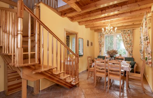 fot. www.airbnb.pl/rooms/53598022?adults=1&children=0&infants=0&check_in=2022-05-20&check_out=2022-05-22&federated_search_id=5ce2eee9-f320-471e-b89b-f0b20797b56a&source_impression_id=p3_1646397077_BQXr4EWlG1RcnNgT. Na zdjęciu jadalnia z kanapą i schodami na górę