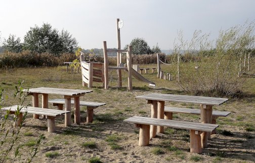 fot. Krzysztof Kozań. Na zdjęciu plac zabaw w Cuplu, stoliki z ławkami, zjeżdżalnia dla dzieci, tor z liną, w oddali rzeka Narew