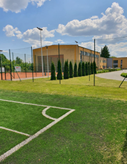 fot. https://spn.nieporet.pl Na zdjęciu fragment boiska do gry  w piłkę nożną, z tyłu fragment boiska do gry w tenisa ziemnego