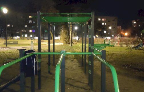 fot. Krzysztof Kozań. Na zdjęciu poręcze równoległe, drążki do podciągania, butelka wody, bluza,  z tyłu zabudowania bloki mieszkalne