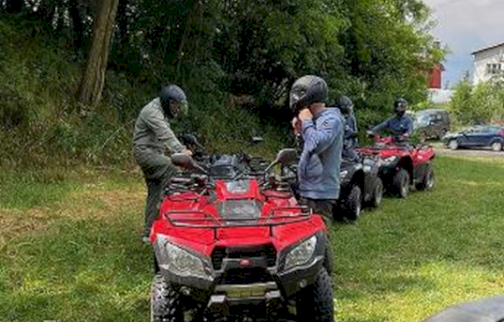 Fot. EVENT EXTREME FORT ROBSON. Na zdjęciu kilka osób w kaskach stoi na trawie obok czerwonych quadów i przygotowuje się do jazdy w zielonej, leśnej okolicy