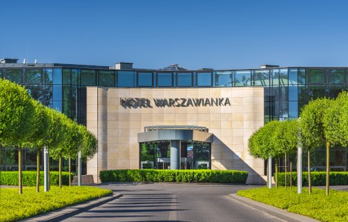 fot. Materiały własne Hotelu Warszawianka. Na zdjęciu główne wejście do hotelu Warszawianka z przeszkloną fasadą oraz terenem zielonym