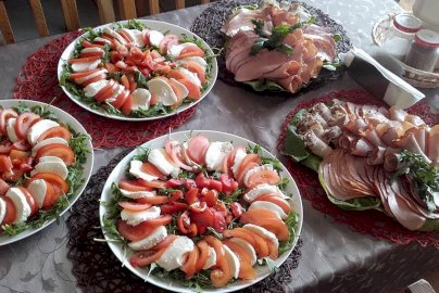 Powiększ obraz: fot. facebook Catering Romanka, https://www.facebook.com/people/Catering-Romanka/100057607743055/. Na zdjęciu półmiski z pomidorami i serem, wędlinami, solniczka, pieprzniczka