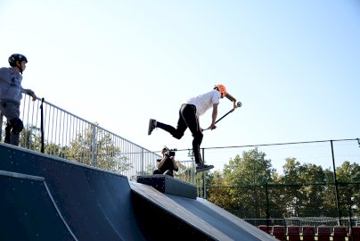 Powiększ obraz: fot. Urząd Miasta Legionowo, www.legionowo.pl/a/stadion-miejski-w-legionowie. Na zdjęciu osoba wykonuje ewolucje na hulajnodze, z tyłu kamerzysta nagrywa film