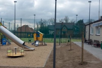 Powiększ obraz: fot. sis.serock.pl. Na zdjęciu zjeżdżalnia rurowa dla dzieci, karuzela, domek dla dzieci z małą zjeżdżalnią, po prawej stronie świetlica, z tyłu fragment boiska do gry w piłkę nożną