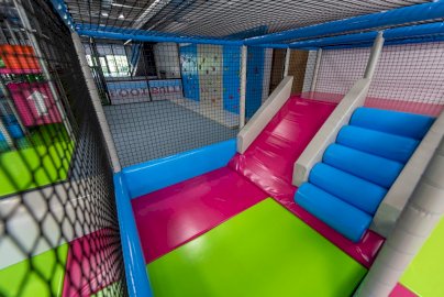 Powiększ obraz: fot. salazabawpiccolo.pl/. Na zdjęciu sala zabaw, urządzenia zabawowe dla dzieci, zjeżdżalnie w formie pochylni, z tyłu ścianka wspinaczkowa, maty