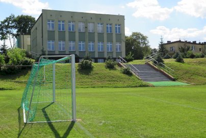 Powiększ obraz: fot. wieliszewsp.szkolnastrona.pl/. Na zdjęciu boisko do gry w piłkę nożną, bramka, na górze szkoła