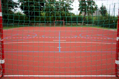 Powiększ obraz: fot. www.jablonna.pl/kultura-i-sport/zawartosc/383/. Na zdjęciu boisko o sztucznej nawierzchni d gry w piłkę nożną, bramki do strzelania, w tle drzewa