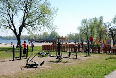 Powiększ obraz: fot. www.nieporet.pl/sport-i-turystyka/obiekty-sportowe/. Na zdjęciu siłownia plenerowa, plac zabaw dla dzieci na Dzikiej Plaży w Nieporęcie