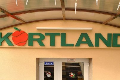 Powiększ obraz: fot. kortland.pl. Na zdjęciu na froncie budynku napis dużymi literami KORTLAND, fragment drzwi wejściowych