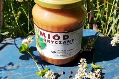 Powiększ obraz: fot. facebook Gospodarstwo Pasieczne "Dębowa Pasieka" - Mateusz Oleksiak, www.facebook.com/Gospodarstwo-Pasieczne-D%C4%99bowa-Pasieka-Mateusz-Oleksiak-551739131993407/. Na zdjęciu słoik miodu gryczanego, obok rosnące kwiaty