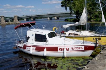 Powiększ obraz: fot. www.ppsm.pl. Łodzie kabinowe przycumowane do brzegu, w tle most w Zegrzu, akwen wodny Jeziora Zegrzyńskiego