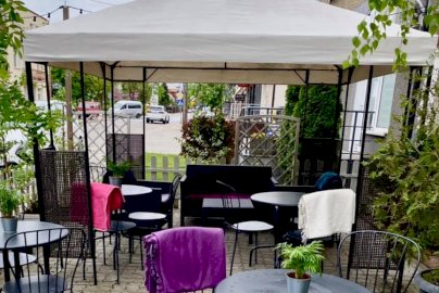 Powiększ obraz: fot. www.slodkiebabki.com.pl. Na zdjęciu kawiarnia, stoliki z krzesełkami, sofa, w tle fragmenty budynków mieszkalnych, samochody osobowe