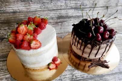 Powiększ obraz: fot. Pracownia Cukiernicza Stachurscy, https://www.facebook.com/pracowniacukiernicza.stachurski. Na zdjęciu dwa torty, po lewej stronie tort śmietankowy z truskawami, po prawej stronie tort z czereśniami