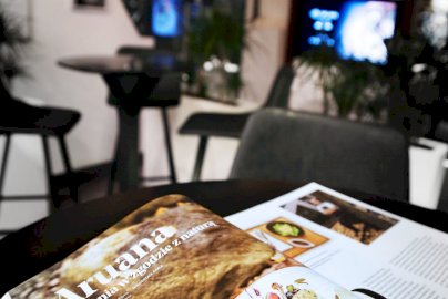 Powiększ obraz: fot. www.hotelnarvil.pl/restauracja/filozofia. Na zdjęciu widok na restaurację Aruana Resturant, napis na książce "Aruana. Kuchnia w zgodzie z naturą"