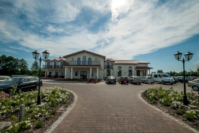 Powiększ obraz: fot. rozany-dwor.pl/fotogaleria. Na zdjęciu hotel, restauracja Różany Dwór. Na zdjęciu widok na hotel Różany Dwór w Wieliszewie, parking z samochodami