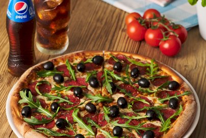 Powiększ obraz: fot. www.dagrasso.pl/legionowo. Na zdjęciu pizza ze składnikami: salami, rukolą i ciemnymi oliwkami, napis, logo DaGrasso
