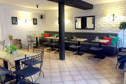 Powiększ obraz: fot. dolcevita-nieporet.pl. Na zdjęciu stoliki z krzesłami, szara sofa
