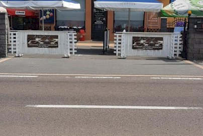 Powiększ obraz: fot. facebook Azyl Cafe, www.facebook.com/azylcafedosin/. Na zdjęciu widok z zewnątrz kawiarni Azyl Cafe , parasole, pod którymi znajdują się ławki ze stolikami