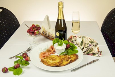 Powiększ obraz: fot. buchnikowachata.pl. Na zdjęciu na stole truskawki, szampan, naleśniki, serwetka