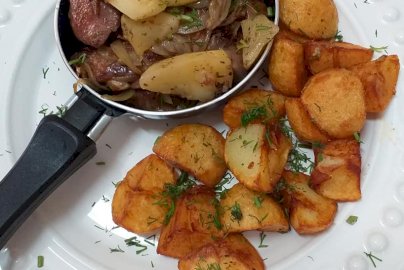 Powiększ obraz: fot. facebook Kuchnia Smaków U Okrasy, https://www.facebook.com/kuchniasmakowuokrasy/?ref=page_internal. Na zdjęciu patelnia, na patelni ziemniaki z mięsem, na białym talerzu pokrojone w kawałki ziemniaki z koperkiem