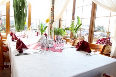 Powiększ obraz: fot. zlotyokon.pl/oferta/restauracja/. Na zdjęciu stół, na nim kieliszki, serwetki, kwiaty
