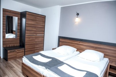 Powiększ obraz: fot. www.bukowiec.eu. Pokój hotelowy z łóżkiem, na łóżkach poduszki, ręczniki, szafa z lustrem po lewej stronie