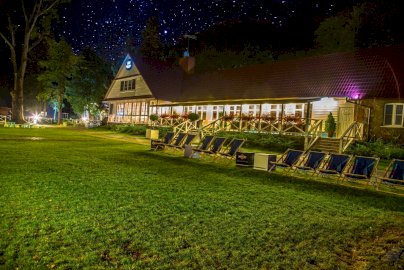 Powiększ obraz: Fot. www.klubmila.pl. Hotel Klub Mila Zegrzynek przy blasku gwiazd na niebie, rozstawione leżaki na trawie