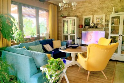Powiększ obraz: fot. www.magnolia-rooms.pl. Niebieska narożna sofa z poduszkami, stolik z fotelami, telewizor